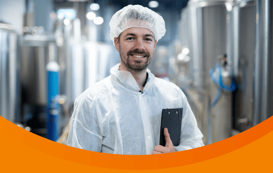 Smiling worker stands in a clean powder processing facility. 